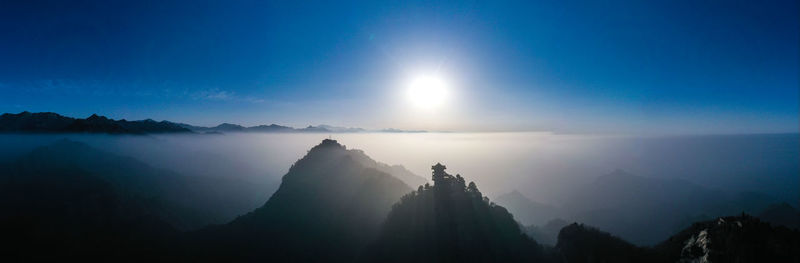 Scenic view of silhouette mountains against blue sky