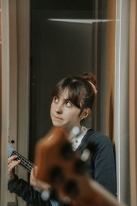 Portrait of woman holding guitar at home