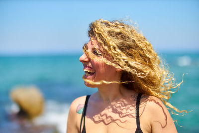 Young woman with curly blond hair at beach