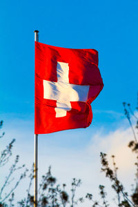 Low angle view of red flag against blue sky