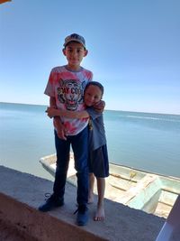 Full length portrait of boy on sea against sky