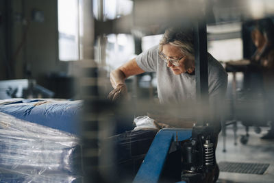 Senior female baker examining flour sacks while working at bakery