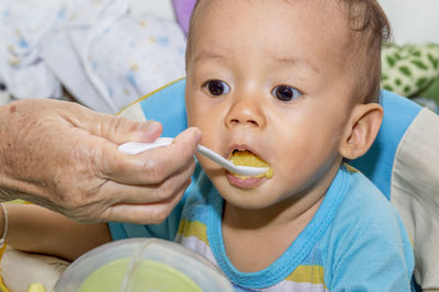 Close-up portrait of cute baby eating man