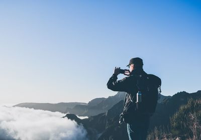 Man photographing on mountain against clear sky