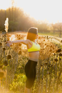 Woman exercising while standing amidst field