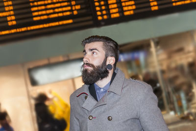 Hipster businessman consult the board of timetable trains