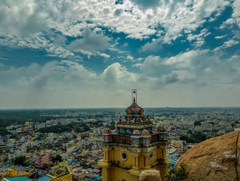 Aerial view of city buildings against cloudy sky