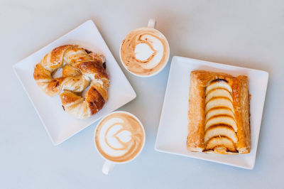 Directly above shot of snacks with cappuccinos served on table