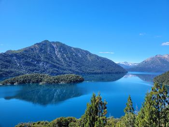 Scenic view of lake and mountains against clear blue sky