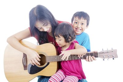 Mother with children playing guitar against white background