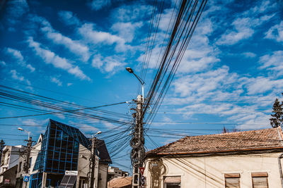 Low angle view of buildings with pylon against cloudy sky