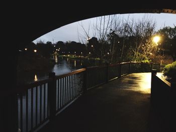 Illuminated bridge over river against sky at night