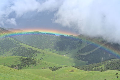 Scenic view of rainbow over landscape against sky