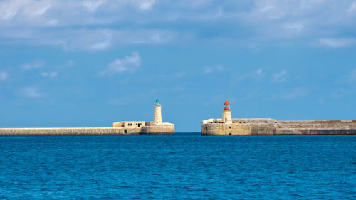 Lighthouse by sea against sky