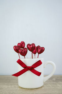 Close-up of red heart shape decoration on table against white background