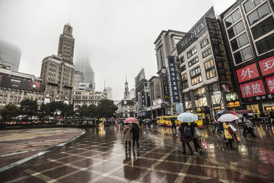 People walking on city street during rainy season