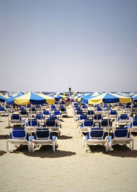 Chairs on beach against clear sky