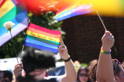 Midsection of people holding multi colored flags