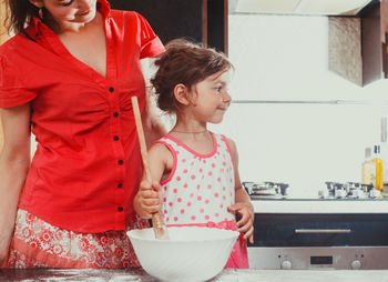 Young woman holding ice cream in bowl at home