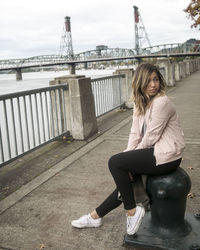 Portrait of young woman sitting on bridge