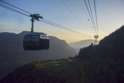 Overhead cable car on mountains against sky during sunset