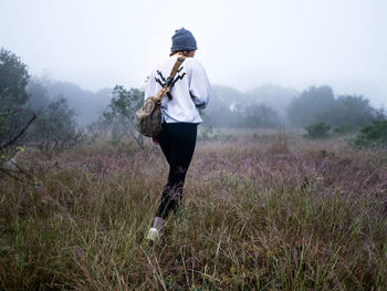 Young woman walking on field against sky