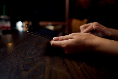 Midsection of person using mobile phone on table