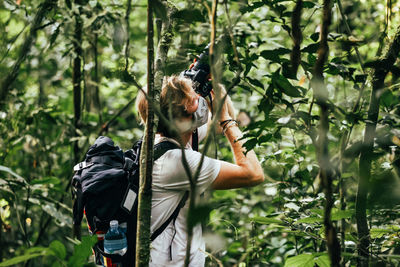 Male photographer takes photograph in jungle.