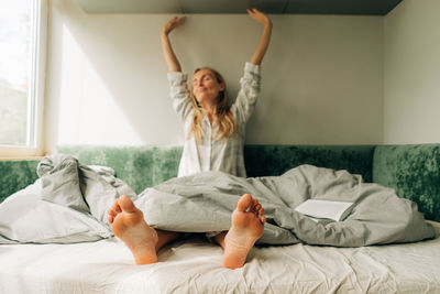 A woman in pajamas stretches after waking up. blurred portrait of a woman, feet in focus.