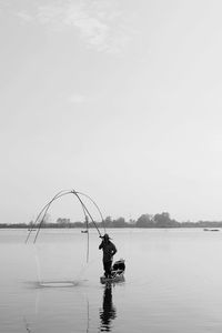 Man fishing in sea against clear sky