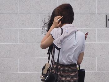 Rear view of woman standing against wall