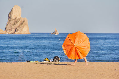 Woman behind umbrella walking on the beach