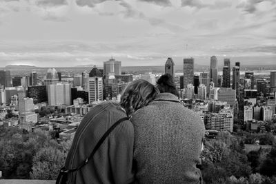 Rear view of couple looking at cityscape against sky