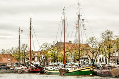 Boats moored at harbor against sky