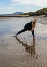 Young woman practicing yoga on the beach in newborough, north wales, uk