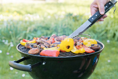 Midsection of person preparing food on barbecue grill