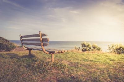 Chair on shore by sea against sky