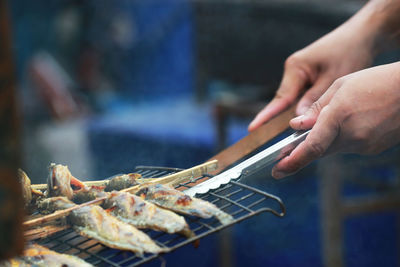 Midsection of person preparing food on barbecue grill