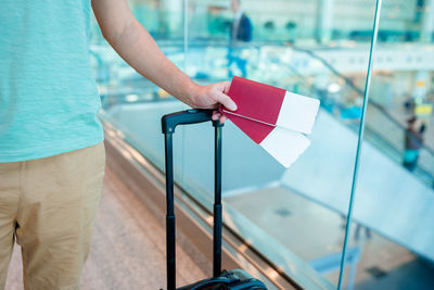 Midsection of man holding tickets in passport