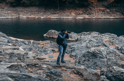 Man standing on rock by lake