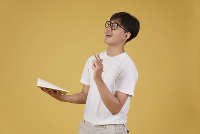 Full length of a boy standing against yellow wall