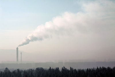 Smoke emitting from stacks in factory against sky