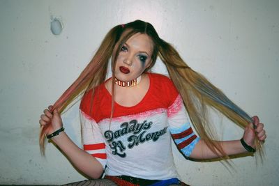 Portrait of beautiful young woman standing against wall