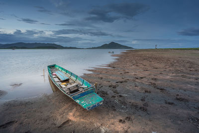 Abandoned boat moored on beach against sky