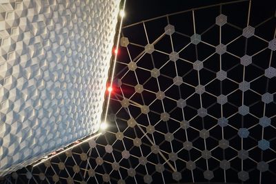 Low angle view of illuminated metal grate at night