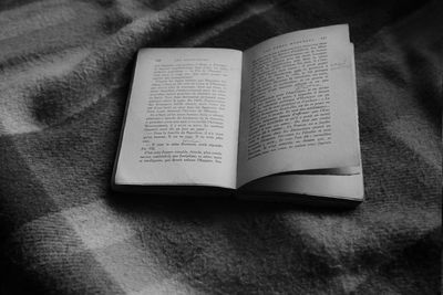 High angle view of open book on bed