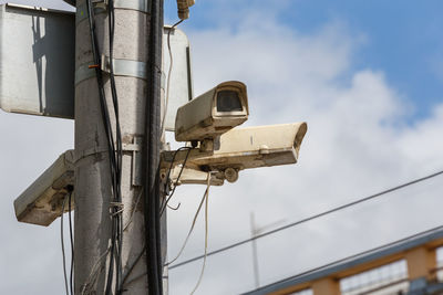 Two old cctv security surveillance cameras on street light pole on blue sky background