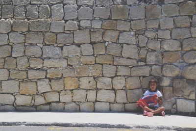 Portrait of teenage girl sitting on stone wall