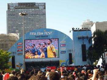 People at music concert in city against clear sky