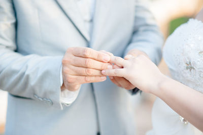 Midsection man putting ring to bride during wedding ceremony